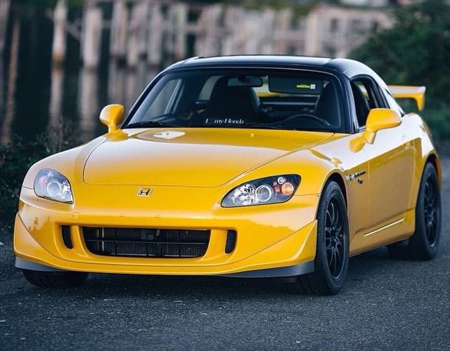 Todd's yellow Honda S2000 with a black hardtop and black wheels, parked at a Pacific Northwest waterfront at dusk.